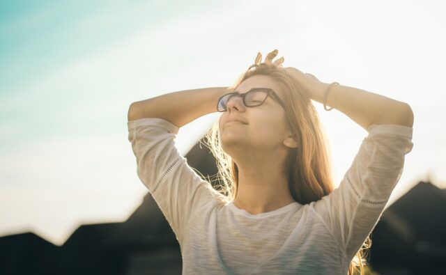 外で空を見上げて清々しそうにする女性